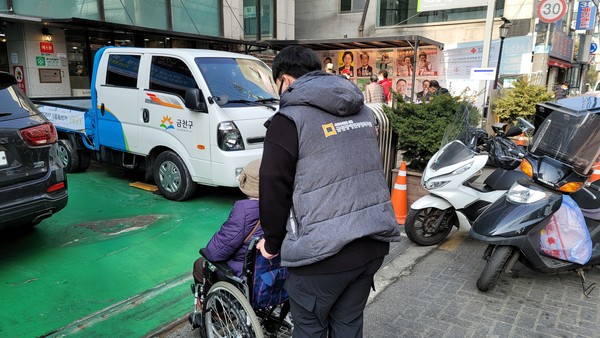 휠체어를 끌고 이동지원하는 모습