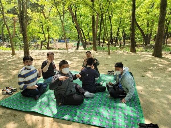 숲에서 돗자리를 깔고 앉아있는 모습