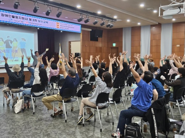 이문오 강사의 장애인식개선교육 중 손을 번쩍 올리고 두팔을 흔드는 사진