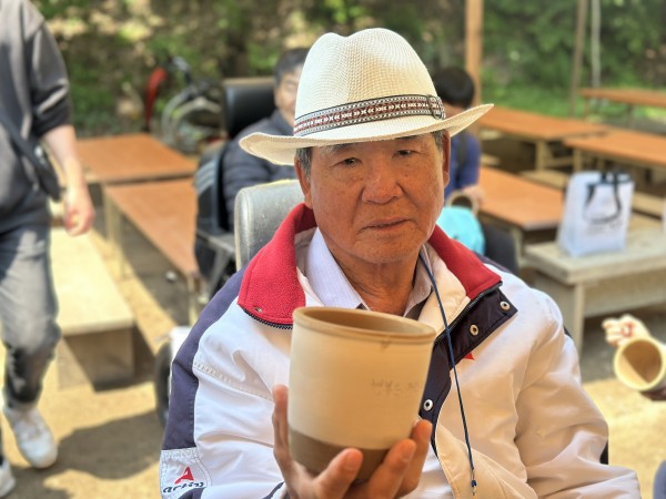 옹기에 글을 작성하고 들고 사진을 찍고 있는 모습