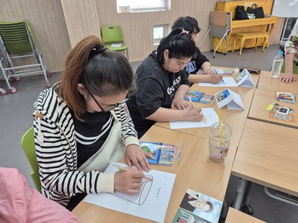 마음을 담은 컵이라는 주제의 활동지 안을 그려 넣는 모습