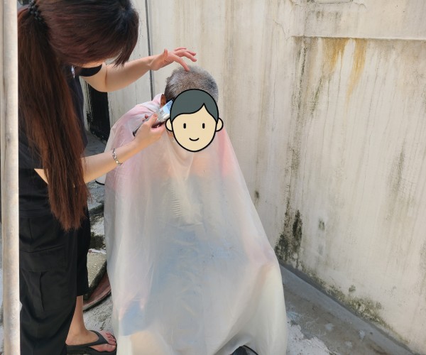 날이 더워 집 앞 마당에서 머리를 자르는 이용인의 모습