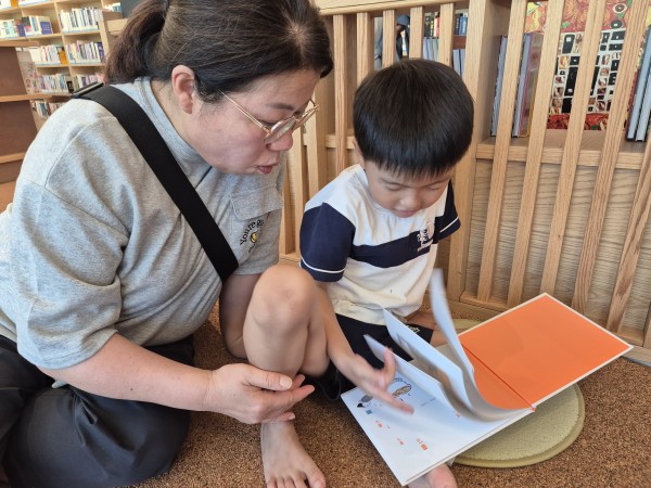 봉사자의 도움을 받아 책을 읽는 모습