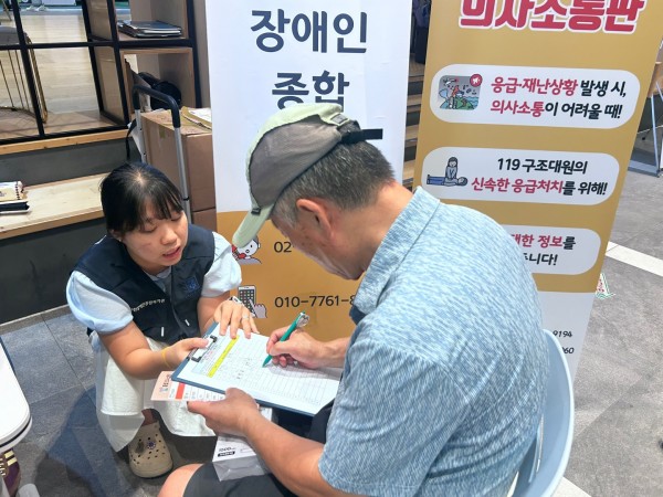 응급의사소통판에 대해 설명을 듣고 참석자 명단에 서명하고 있는 사진