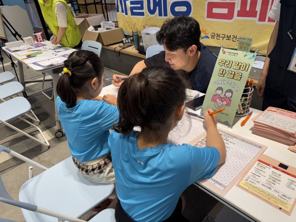 아이들이 응급의사소통판 교육을 듣고 있는 사진