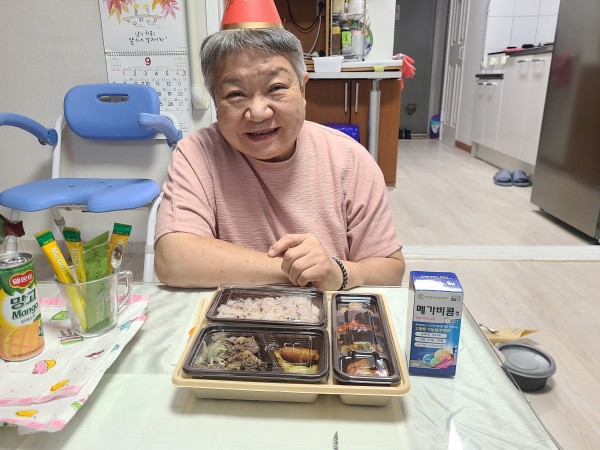 식탁에 앉아 선물과 사진을 찍는 이용인의 모습
