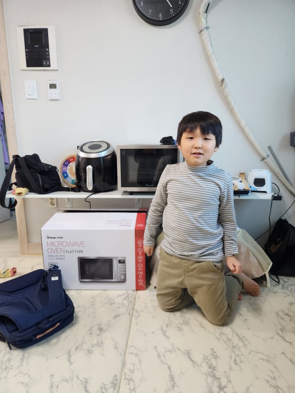 새 전자레인지와 사진을 찍는 아동의 모습
