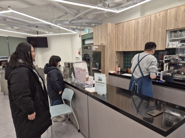 선배 바리스타가 커피 샷을 추출하는 과정을 관찰하는 모습