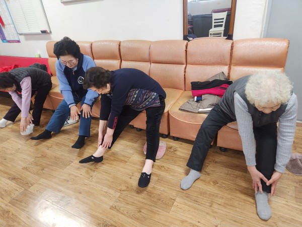 다리 스트레칭을 위해 양손을 발 끝으로 쭉쭉 뻗는 중