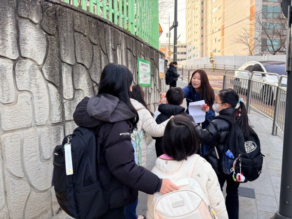 여러명의 아이들에게 그림그리기 대회 안내하는 모습