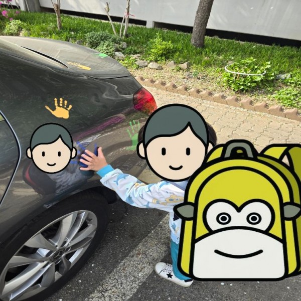 자동차에 붙어있는 손바닥 스티커에 맞춰 손을 비교해보는 아이의 모습