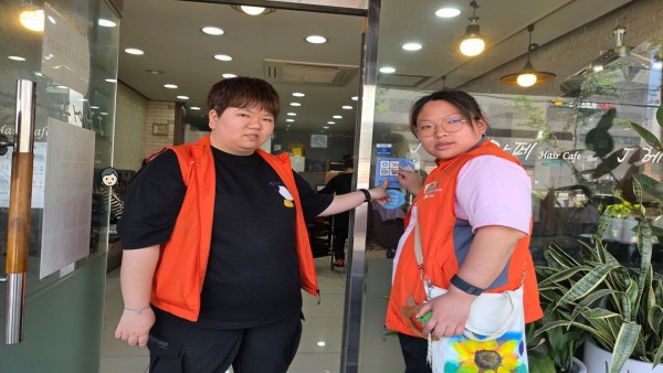 제이헤어카페 입구에서 AAC 존 스티커를 가리키는 모습