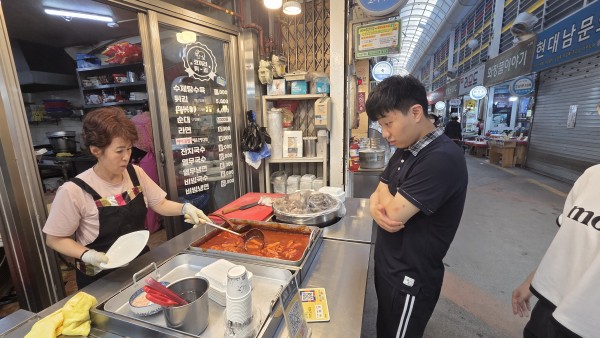 시장 분식점에서 떡볶이를 구입하는 모습