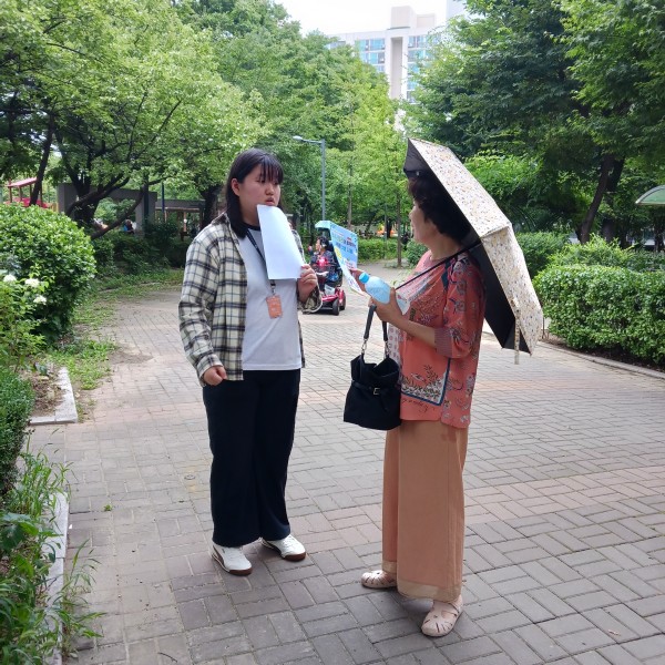 지역주민들에게 내일 행사를 홍보하는 실습생