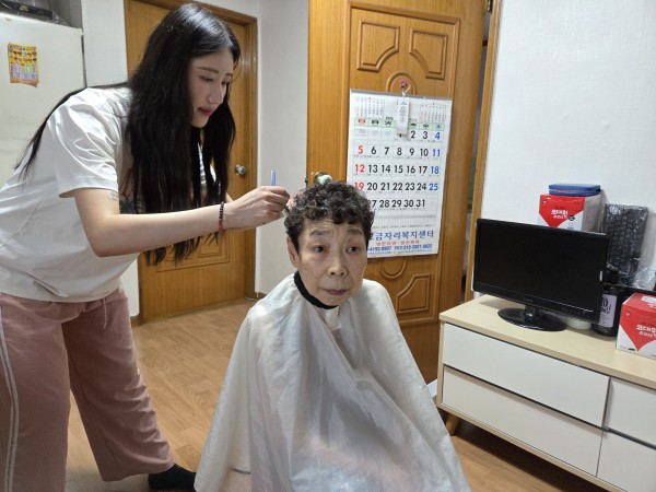 즐겁게 대화하며 미용을 하는 대상자와 미용봉사자