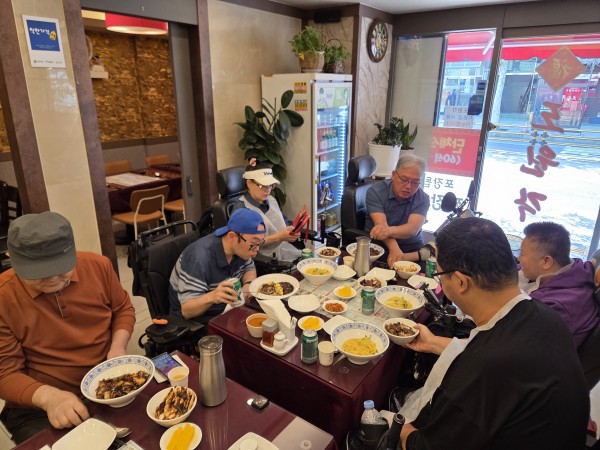 스쿠터를 탑승한 상태로 식탁에 앉아 식사를 하는 모니터링단의 모습