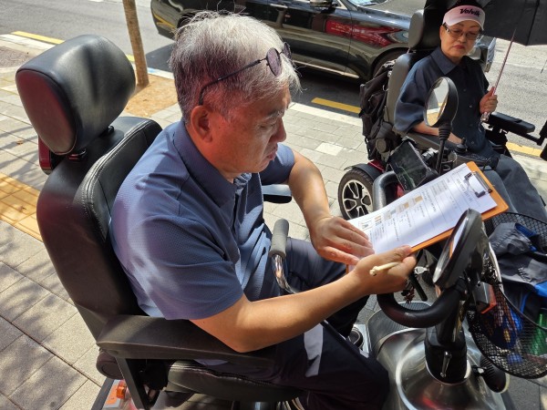 무장애 상점 확인 체크리스트를 작성하는 모니터링단 단원의 모습